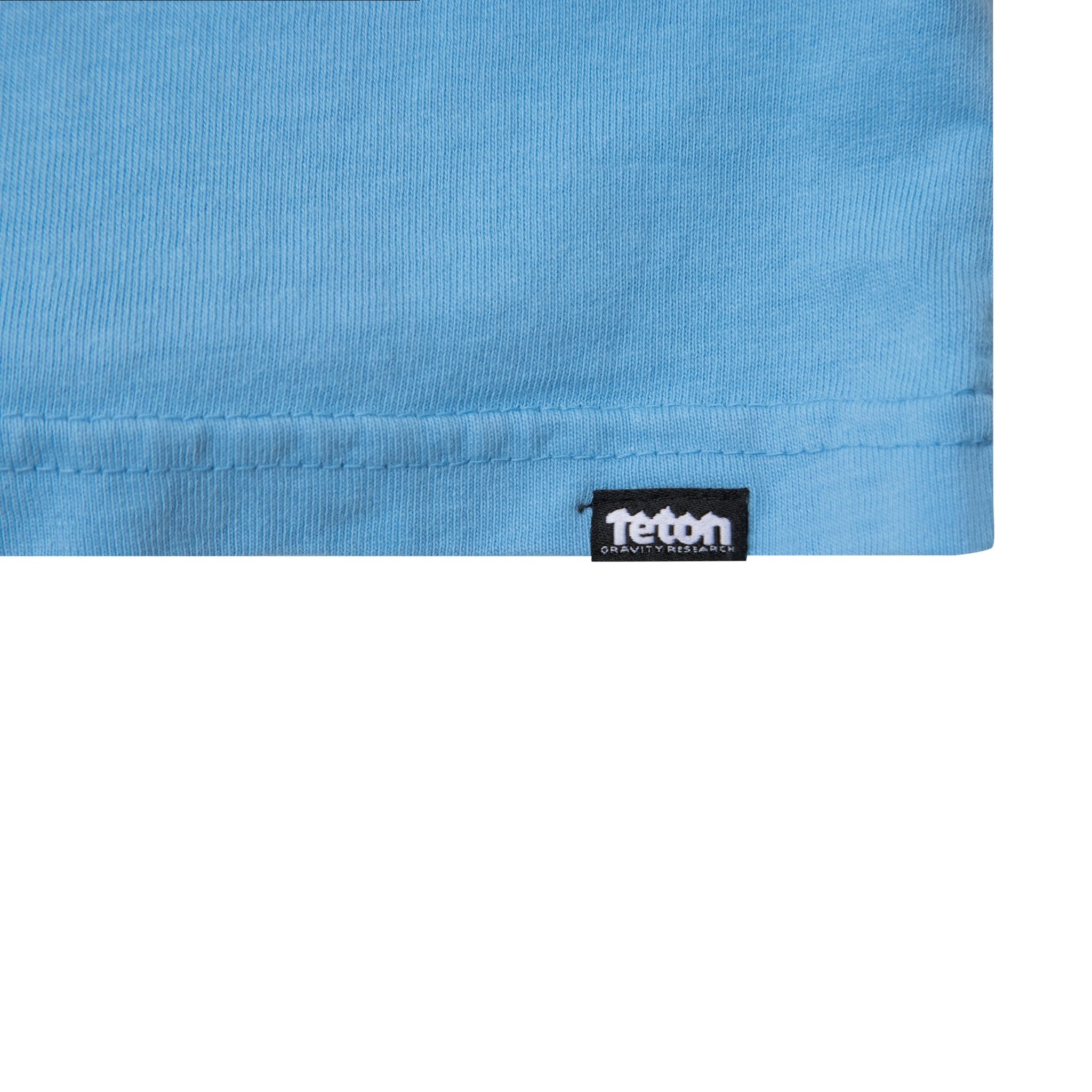Show the small Teton Gravity Research logo tag on the bottom left of shirt. #color_baby blue