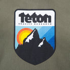 Picture of the logo on the front of the sweatshirt. Shoes the Teton Gravity Research logo with the Grand Tetons and a sunset in the background. #color_Army Green